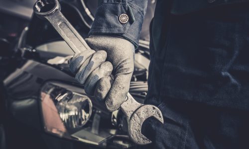 Fixing the Car Concept Fixing the Car Concept. Mechanic with Large Wrench is About To Start His Car Maintenance and Fix Work.
